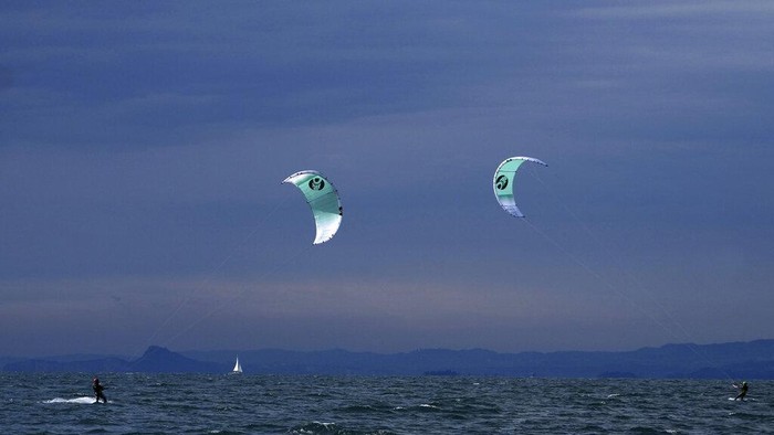 Surga Peselancar Angin di Danau Italia A kitesurfer surfs Lake Garda near Brenzone sul Garda, northern Italy, Saturday, Oct. 9, 2021. (AP Photo/Matthias Schrader)