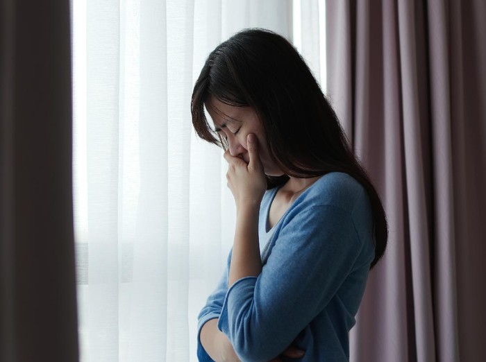 asian depression sad woman is standing by windows alone at home and thinking negative thoughts