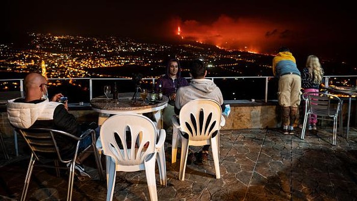 Santainya Warga Spanyol Amati Gunung Meletus LA PALMA, SPAIN - OCTOBER 07: The Cumbre Vieja volcano is seen between the towns of Los Llanos (L) and Tazacorte (R) on October 7, 2021 in La Palma, Spain. Cumbre Vieja Volcano erupted on September 19, shutting down the airport twice due to the volcanic ash. The numerous lava flows destroyed hundreds of hectares, but also formed peninsulas of volcanic rock, extending the surface of the island. (Photo by Marcos del Mazo/Getty Images)
