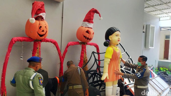Satpol PP dan BPB Linmas Surabaya membongkar boneka Squid Game. Pembongkaran dilakukan karena boneka dari serial tersebut dianggap menimbulkan kerumunan dan juga tak memiliki izin.