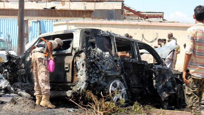 Yemeni security forces and rescue teams gather around the carcass of a burnt car following an explosion that hit Yemens southern port city of Aden, on October 10, 2021. - Five people have been killed in a car-bomb attack targeting the governor of Aden, the seat of Yemens internationally recognised government, Yemeni security sources said. (Photo by Saleh Al-OBEIDI / AFP)