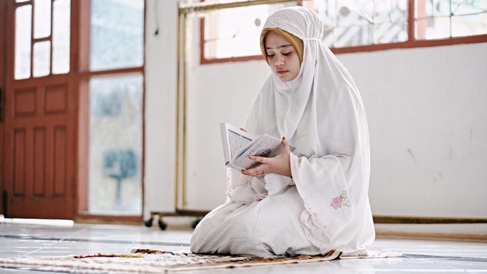 Young beautiful Muslim Woman Praying In Mosque.
