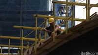 Seorang pekerja tengah menyelesaikan pembangunan jembatan penyeberangan orang (JPO) bertema kapal pinisi di Jalan Sudirman, Jakarta.
