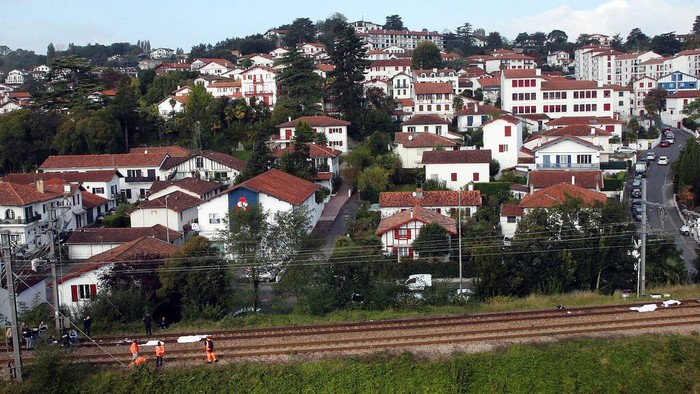Istirahat di Rel, Migran di Prancis Tertabrak Kereta Api Police officers investigate as bodies are covered with blankets after a train accident in Ciboure, near Saint Jean de Luz, southwestern France, Tuesday, Oct.12, 2021. A train hit and killed three people and seriously injured another person in southwestern France on Tuesday morning. A local mayor said the victims were thought to be migrants who were resting on the tracks. (AP Photo/Bob Edme)