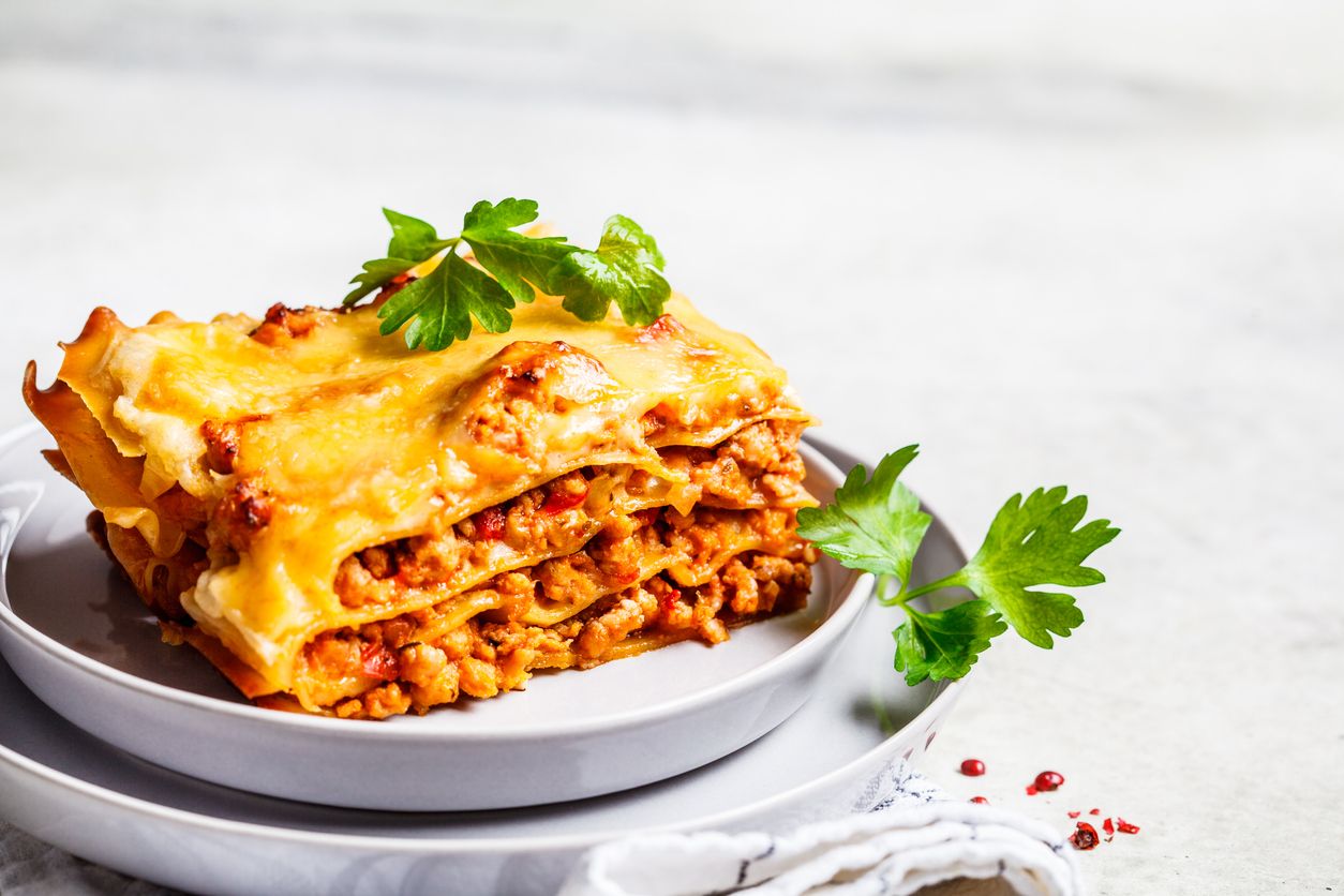 Close-up of classic meat lasagna with cheese on a gray plate. Italian food concept.