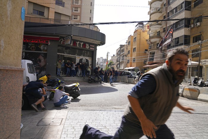 Warga berhamburan menyelamatkan diri saat terjadi bentrokan bersenjata di Ibu Kota Beirut, Lebanon. Tembakan dari atap gedung itu menyasar ke kelompok demonstran Syiah. (AP Photo/Hassan Ammar)