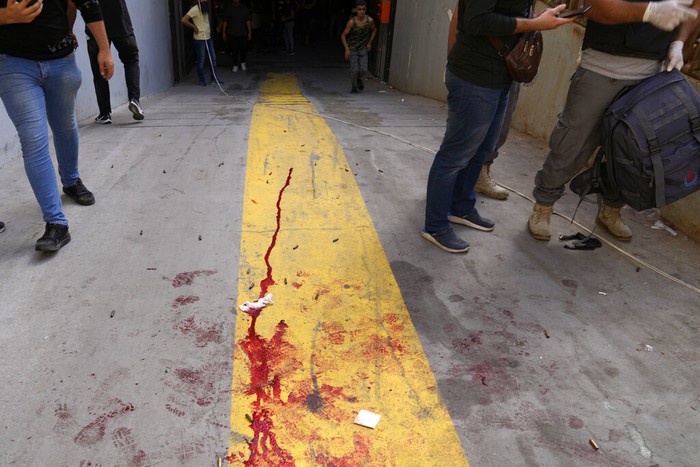 Detik-detik Bentrokan Bersenjata di Beirut Warga berhamburan menyelamatkan diri saat terjadi bentrokan bersenjata di Ibu Kota Beirut, Lebanon. Tembakan dari atap gedung itu menyasar ke kelompok demonstran Syiah. (AP Photo/Hassan Ammar)