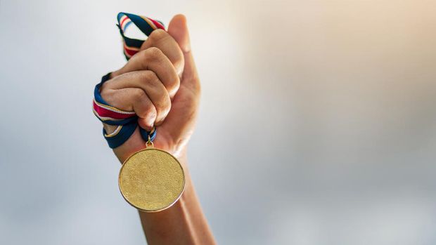 Hand holding gold medal on sky background, The winner and successful concept