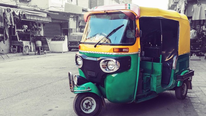 Bajaj di India Traditional yellow green tuk tuk taxi on the street. Indian public transport on the streets of new Delhi.