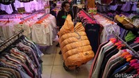 Pedagang mengangkut karung besar berisi pakaian bekas yang akan dijual di pasar tersebut.