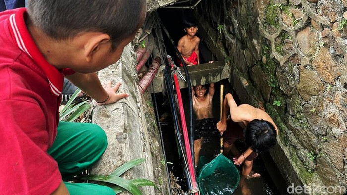 Nekat, Anak-anak Cari Ikan di Selokan Jalur Kabel Optik Minimnya sarana bermain, sejumlah anak nekat mencari ikan di dalam selokan yang berisi kabel optik di Jalan Gatot Subroto, Jakarta, Jumat (15/10/2021).