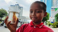 Seorang anak menunjukkan seekor ikan yang berhasil ditangkap di selokan tersebut.