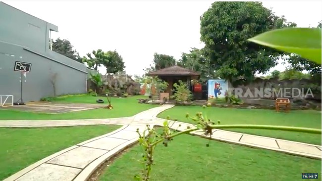 Halaman rumah cukup luas, bahkan terdapat sebuah lapangan basket. Halaman ini juga dimanfaatkan Narji untuk menyalurkan hobinya bercocok tanam. Tumbuhan yang dikoleksinya pun bukan kaleng-kalengan. Narji memiliki tanaman yang satu daunnya bisa dihargai hingga belasan juta rupiah. (Foto: YouTube/Trans7 Official)