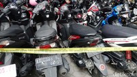 Pagar kantor dan kendaraan roda dua yang terparkir nampak digaris polisi. Di depan kantor, nampak terparkir mobil polisi.