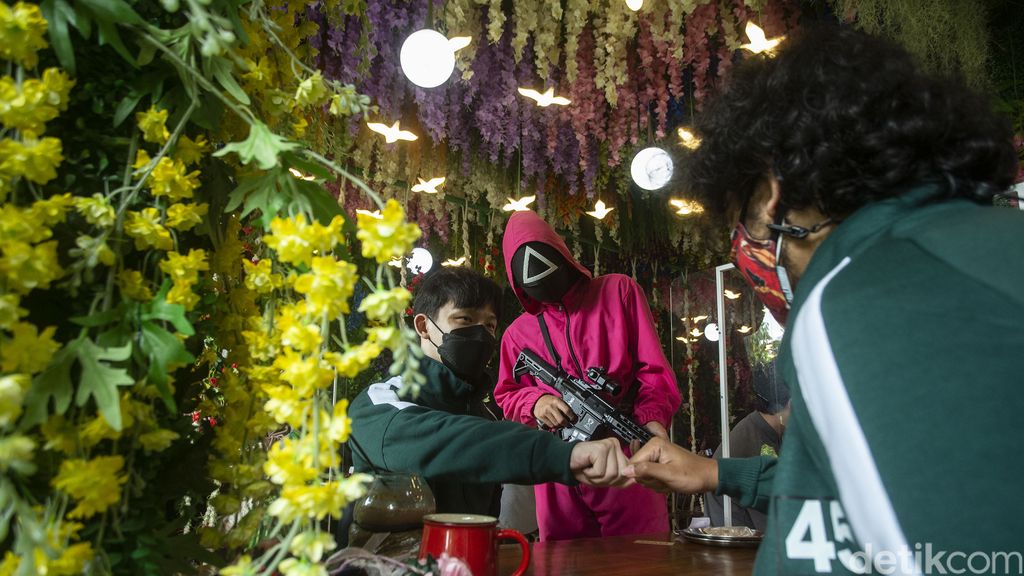 Pelayan dengan menggunakan kostum ala film Squid Game meletakkan pesanan di Strawberry Cafe, Jakarta Barat, Sabtu (16/10/2021). Usai mengadopsi konsep film Squid Game, cafe ini kebanjiran pengunjung.