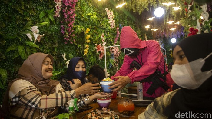 Pelayan dengan menggunakan kostum ala film Squid Game meletakkan pesanan di Strawberry Cafe, Jakarta Barat, Sabtu (16/10/2021). Usai mengadopsi konsep film Squid Game, cafe ini kebanjiran pengunjung.