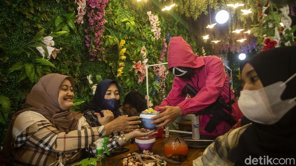 Pelayan dengan menggunakan kostum ala film Squid Game meletakkan pesanan di Strawberry Cafe, Jakarta Barat, Sabtu (16/10/2021).