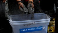 Cat dicampur dengan abu kebakaran hutan. Campuran ini menjadi bahan untuk membuat mural hitam putih.