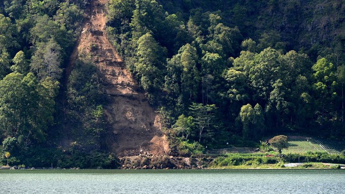 Petugas dan warga mengamati rumah yang rusak tertimbun longsoran bukit akibat gempa di kawasan Trunyan, Kintamani, Bangli, Bali, Sabtu (16/10/2021). Gempa bumi dengan magnitudo 4,8 SR yang terjadi di darat pada jarak delapan kilometer barat laut Karangasem dengan kedalaman 10 km pada Sabtu (16/10) pukul 04.18 Wita mengakibatkan sejumlah bangunan di Bali rusak dan tiga orang meninggal dunia. ANTARA FOTO/Fikri Yusuf/hp.