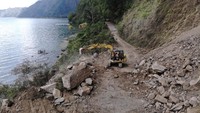 Sebuah alat berat dikerahkan untuk membersihkan material longsoran bukit akibat gempa bumi Karangasem Bali yang menutup jalan di kawasan Kintamani, Bangli, Bali, Minggu (17/10/2021).