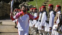 Atlet ski, Ioannis Antoniou yang membawa obor dan ranting pohon zaitun melewati penjaga keamanan kepresidenan Yunani.