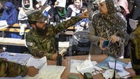 Pejuang Taliban berbicara kepada salah satu warga yang mengantri layanan paspor di Kabul.  Antrian bertambah sejak pemerintah mengumumkan bakal menerbitkan berkas paspor yang tertunda saat peralihan kekuasaan, Agustus lalu.