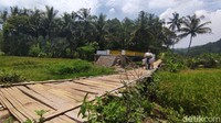 Saat ini, warga masih mempergunakan jembatan lama terbuat dari bambu yang berada di sampingnya. Meski berbahaya karena tak ada pembatas, warga tak punya pilihan lain.