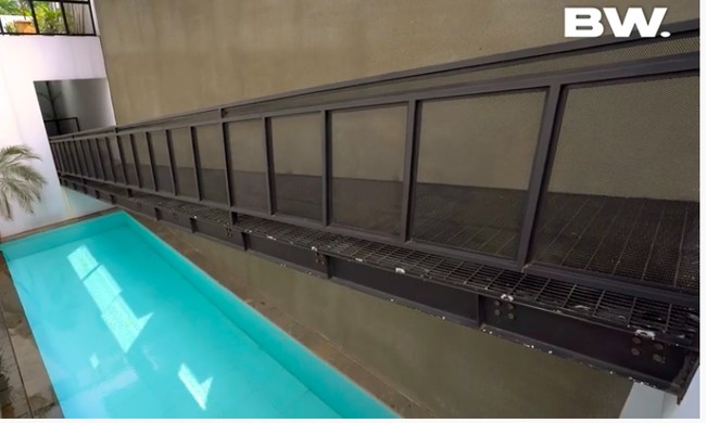 Kolam renang tepat berada di bawah tangga bergaya industrial yang mengarah ke pintu masuk rumah di lantai 2. (Foto: YouTube/Boy William)