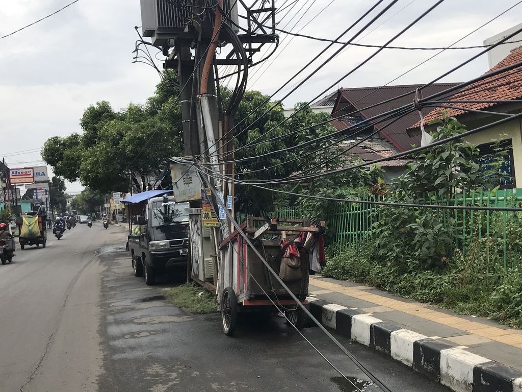Tiang makan jalan dan kabel smerawut di Jl WR Supratman, tapatnya di dekat SDN Pondok Ranji 01.
