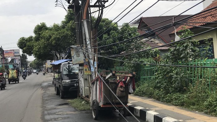 Tiang makan jalan dan kabel smerawut di Jl WR Supratman, tapatnya di dekat SDN Pondok Ranji 01.