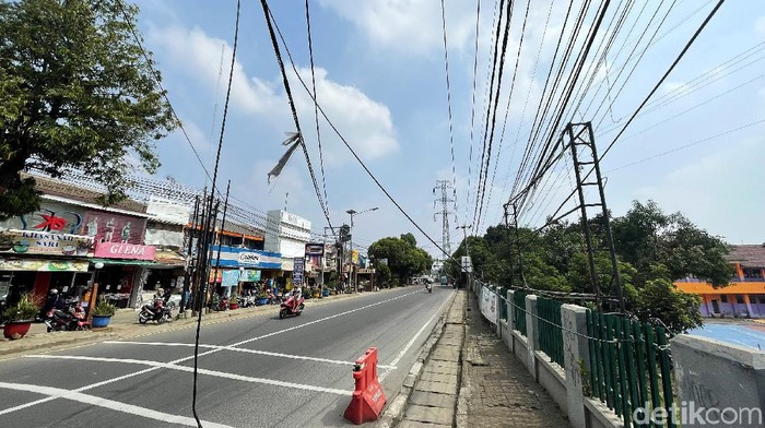 Kabel menjuntai rendah di Jalan Nusantara Raya, Depok, Selasa (19/10/2021), dinilai membahayakan bagi warga yang melintas.