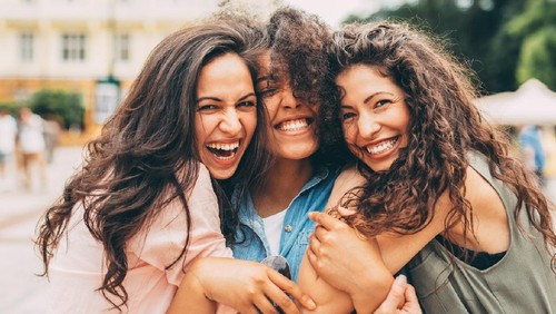 Three best friends hugging each other in the city.