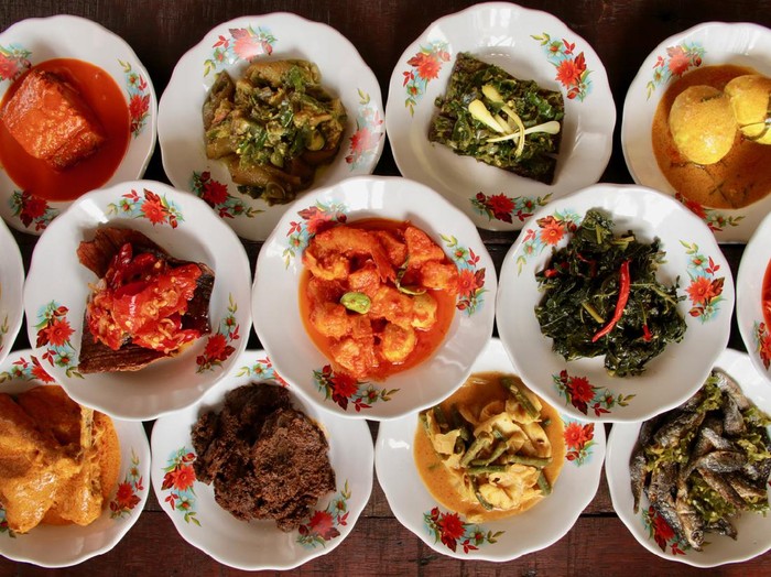 Assortment of Minangkabau dishes served on the table in ‘hidang’ style; means serving the eatery’s menu on the table. The dishes are plated on small ceramic plates and stacked as to save some spaces on the table.