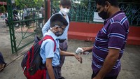Sebelum memasuki kawasan sekolah, para siswa akan lebih dahulu diukur suhu tubuhnya.