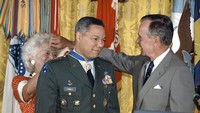 Presiden George Bush disaksikan Ibu Negara Barbara Bush mengalungkan bintang penghargaan kepada Colin Powell (3/7/1991).  Powell menjabat sebagai Menlu AS era Presiden George W. Bush pada 2001-2005. (AP Photo/Doug Mills)