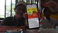 Warga menunjukkan sebaran promo makan gratis melalui gawainya di rumah makan Soto Seger Boyolali Hj. Amanah, Lebak Bulus, Jakarta, Selasa (19/10/2021). ANTARA FOTO/Indrianto Eko Suwarso