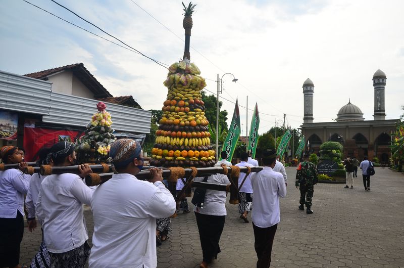 Warga memikul gunungan berisi nasi bungkus daun jati serta buah-buahan saat tradisi Ampyang Maulid di Desa Loram Kulon, Jati, Kudus, Jawa Tengah, Selasa (19/10/2021). Tradisi Ampyang Maulid merupakan peringatan hari kelahiran Nabi Muhammad SAW setiap tanggal 12 Robiul Awwal dengan mengarak gunungan berisi nasi, lauk serta buah-buahan menuju masjid untuk didoakan dan dimakan bersama-sama. ANTARA FOTO/Yusuf Nugroho/rwa.