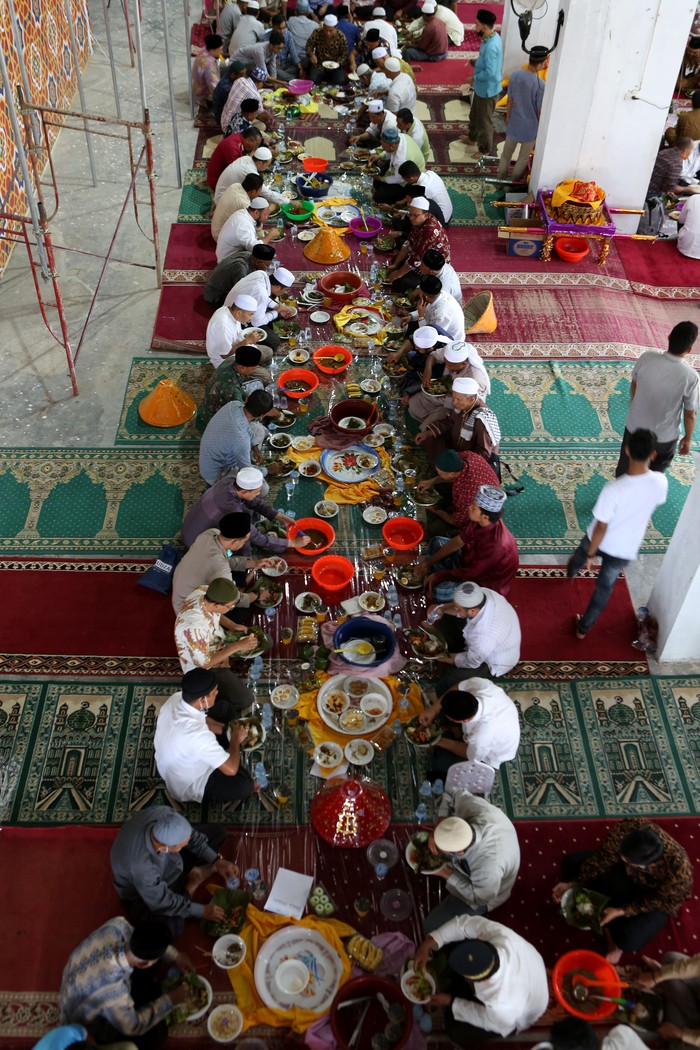 Warga menikmati makanan yang disajikan pada peringatan Maulid Nabi Muhammad SAW di Masjid Jamik Lueng Bata, Banda Aceh, Aceh, Selasa (19/10/2021). Pada setiap perayaan hari kelahiran (maulid) Nabi Muhammad SAW yang berlangsung selama tiga bulan di Aceh, warga selain menyiapkan berbagai makanan dengan menu utama Kuah Beulangong (kari daging sapi atau kambing dengan bumbu khas) untuk dinikmati bersama juga menggelar zikir, menyantuni anak yatim, fakir dan miskin. ANTARA FOTO / Irwansyah Putra/aww.