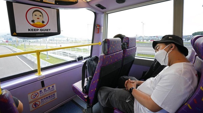 Ada Wisata Bus Tidur Untuk Warga Kurang Istirahat di Hong Kong A passenger poses for a photo in front of a double-decker bus she got on board, in Hong Kong, Saturday, Oct. 16, 2021. Travel-starved, sleep-deprived residents might find a new Hong Kong bus tour to be a snooze. The 76-kilometer (47-mile), five-hour ride on a regular double-decker bus around the territory is meant to appeal to people who are easily lulled asleep by long rides. It was inspired by the tendency of tired commuters to fall asleep on public transit. The banner reads: