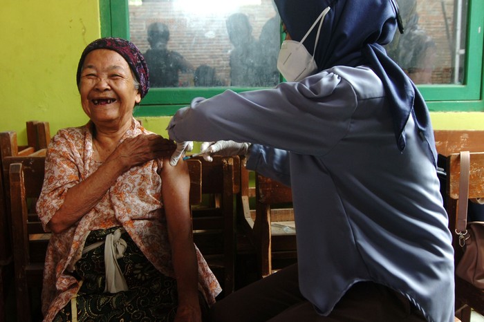 Personel kepolisian menuntun nenek bernama Tarmi usai melakukan penyuntikan di rumahnya Kelurahan Kalinyamat Wetan, Tegal, Jawa Tengah, Kamis (21/10/2021). Tarmi merupakan lansia tertua dengan usia 102 tahun yang mengikuti vaksinasi COVID-19 di Kota Tegal. ANTARA FOTO/Oky Lukmansyah/foc.