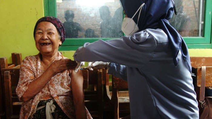 Personel kepolisian menuntun nenek bernama Tarmi usai melakukan penyuntikan di rumahnya Kelurahan Kalinyamat Wetan, Tegal, Jawa Tengah, Kamis (21/10/2021). Tarmi merupakan lansia tertua dengan usia 102 tahun yang mengikuti vaksinasi COVID-19 di Kota Tegal. ANTARA FOTO/Oky Lukmansyah/foc.