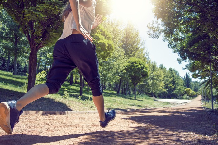 Ilustrasi Olahraga Sprint Low angle shot of a running woman on a path in the park - Healthy lifestyle