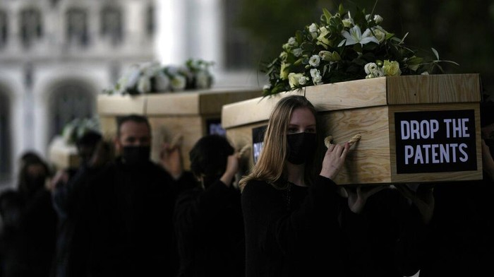 Global Justice campaigners carry fake coffins to highlight the number of COVID-19 deaths globally, in London, Tuesday, Oct. 12, 2021. Britain is taking part in a World Trade Organisation intellectual property meeting to boost the number of vaccinations world wide. The campaigners want large pharmaceuticals companies to drop patents on COVID-19 drugs to allow poorer nations to vaccinate their populations. (AP Photo/Alastair Grant)