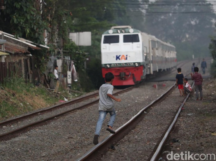 Seorang anak terlihat sedang berlari di atas rel kereta api Bandung.