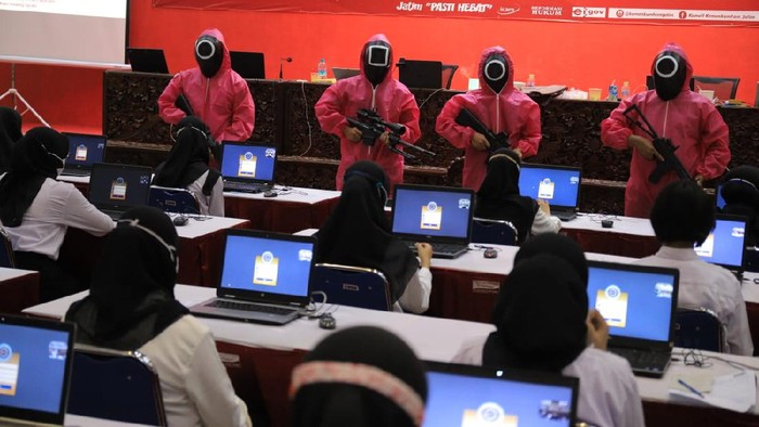 Belasan pink soldier ala Squid Game muncul dalam Seleksi Kompetensi Dasar (SKD) CPNS Kemenkumham Jatim. Bukan untuk ikut seleksi, tapi mereka mengawal para peserta di sela-sela tes Formasi Penjaga Tahanan dan Pemeriksa Keimigrasian.