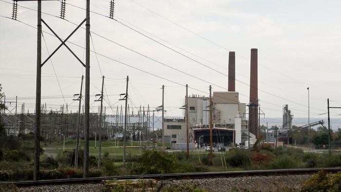 CORRECTS SPELLING OF GREENIDGE - A brief patch of early morning sunlight brightens the landscape around the Greenidge Generation power plant on the banks of Seneca Lake, Friday, Oct. 15, 2021, in Dresden, N.Y. One Bitcoin mining operation in central New York came up with a novel solution in finding cheap energy to run the power-gobbling computer arrays that create and transact cryptocurrency: It took over Greenidge Generation which now produces about 44 megawatts to run 15,300 computer servers, plus additional electricity it sends into the states power grid. (AP Photo/Julie Jacobson)