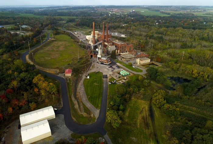 Cryptocurrency Power Plant CORRECTS SPELLING OF GREENIDGE - A brief patch of early morning sunlight brightens the landscape around the Greenidge Generation power plant on the banks of Seneca Lake, Friday, Oct. 15, 2021, in Dresden, N.Y. One Bitcoin mining operation in central New York came up with a novel solution in finding cheap energy to run the power-gobbling computer arrays that create and transact cryptocurrency: It took over Greenidge Generation which now produces about 44 megawatts to run 15,300 computer servers, plus additional electricity it sends into the state's power grid. (AP Photo/Julie Jacobson)