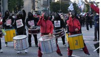 Anggota serikat dalam pakaian Squid Game terlihat memukul drum dengan musik keras dan menari. Foto: Dok. Twitter @quicktake