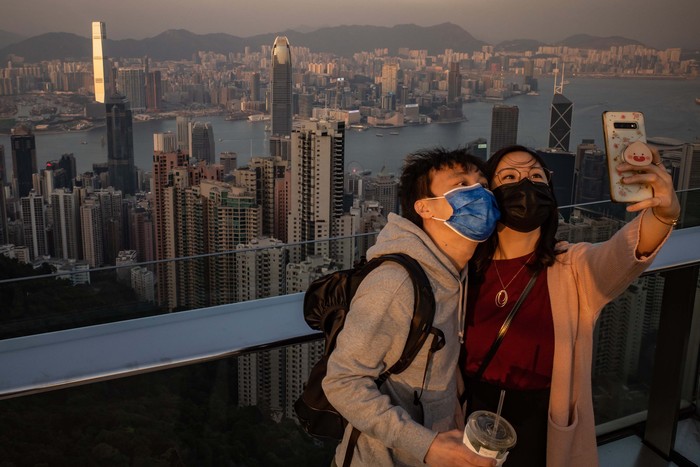 HONG KONG, CHINA - DECEMBER 02: A couple wearing protective masks take a selfie at an observation deck at Victoria Peak on December 2, 2020 in Hong Kong, China. Hong Kong government on Tuesday announced a tightening of the rules for group gatherings, effective for the next 14 days.(Photo by Anthony Kwan/Getty Images)