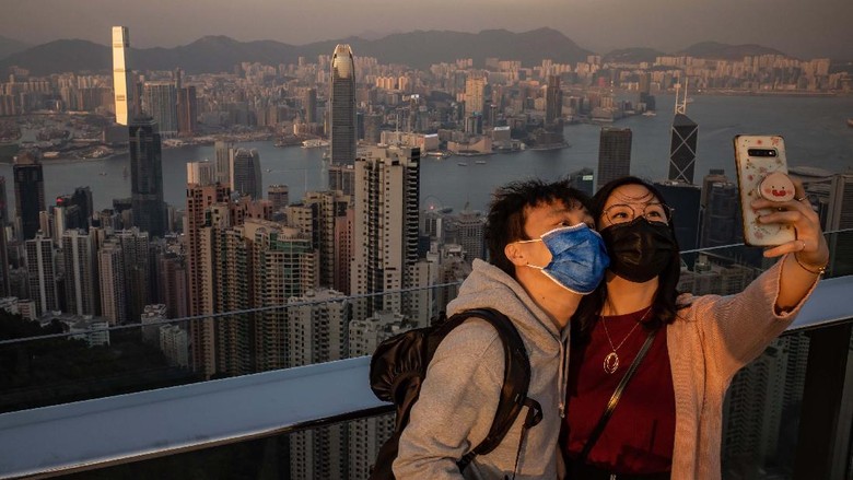 Destinasi Wisata Terkemuka Asia 2021 HONG KONG, CHINA - DECEMBER 02: A couple wearing protective masks take a selfie at an observation deck at Victoria Peak on December 2, 2020 in Hong Kong, China. Hong Kong government on Tuesday announced a tightening of the rules for group gatherings, effective for the next 14 days.(Photo by Anthony Kwan/Getty Images)